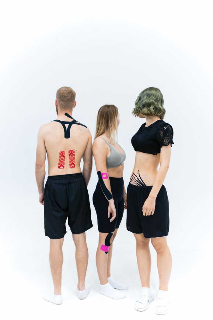 Three athletes with kinesiology tape applied, standing against a white background.